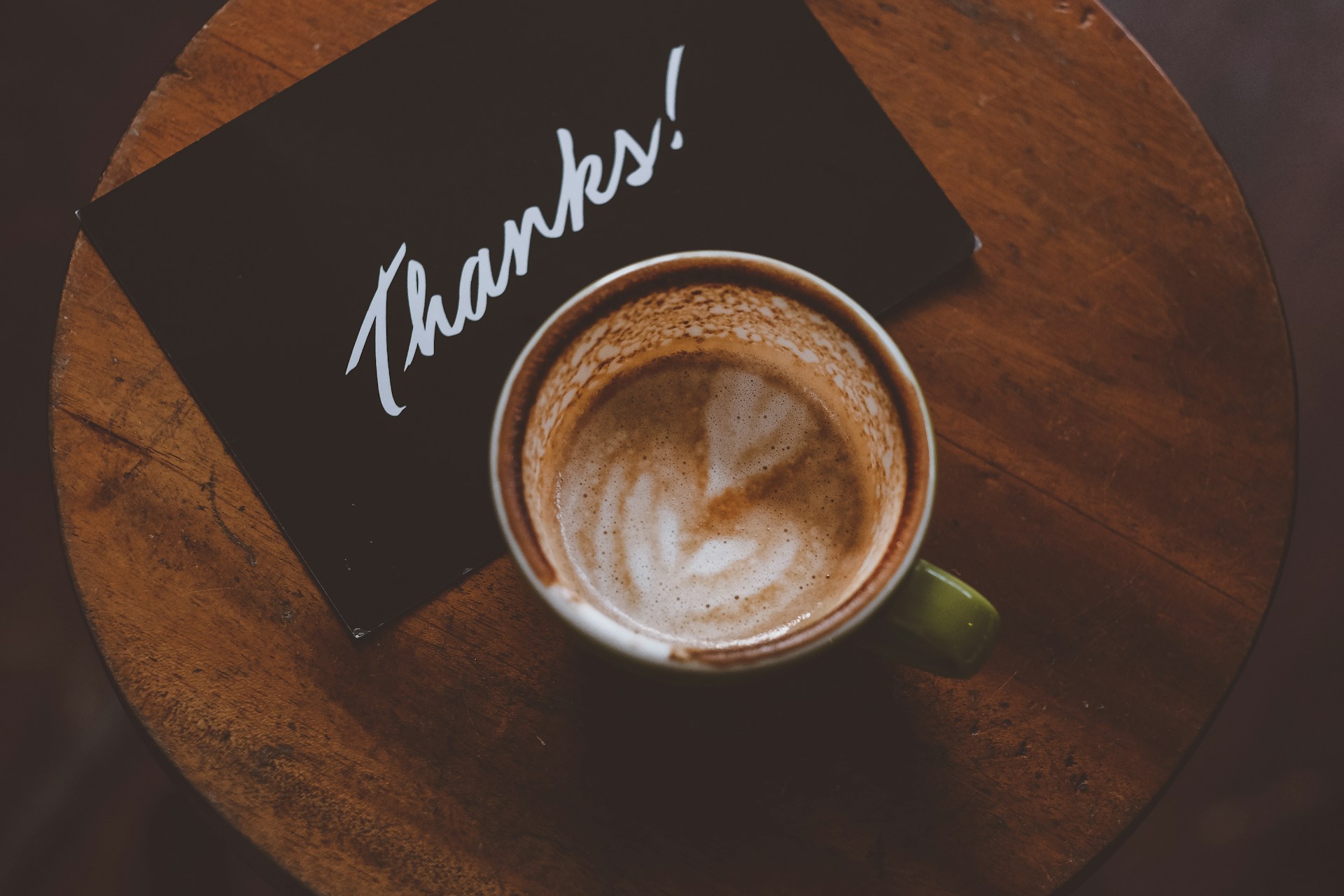 Postkarte mit der dem Wort “Thanks” auf einem Kaffeetisch unter einer leeren Kaffeetasse