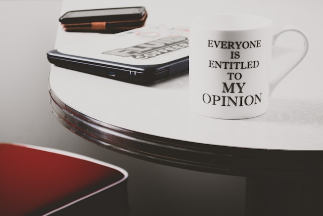 Tasse of einem Bürotisch mit der Aufschrift "Everyone is entitled to my opinion"