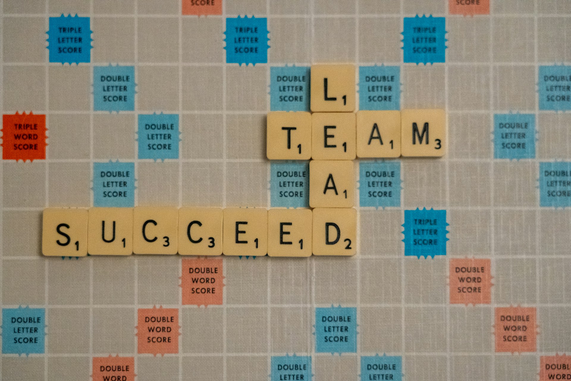 Scrabble-Spielbrett mit den Steinen “TEAM LEAD SUCCEED”